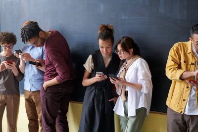 Grup de persoane care navighează pe telefoane, ilustrând importanța unei bune experiențe pe pagină și a optimizării Core Web Vitals.