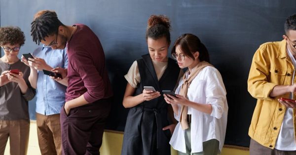 Grup de persoane care navighează pe telefoane, ilustrând importanța unei bune experiențe pe pagină și a optimizării Core Web Vitals.