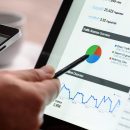 Mână care analizează grafice și date SEO pe un laptop, esențială pentru a înțelege și demonta mitul canibalizarea cuvintelor cheie și a identifica adevăratele probleme de ranking.