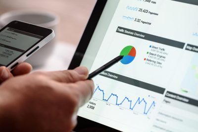Mână care analizează grafice și date SEO pe un laptop, esențială pentru a înțelege și demonta mitul canibalizarea cuvintelor cheie și a identifica adevăratele probleme de ranking.