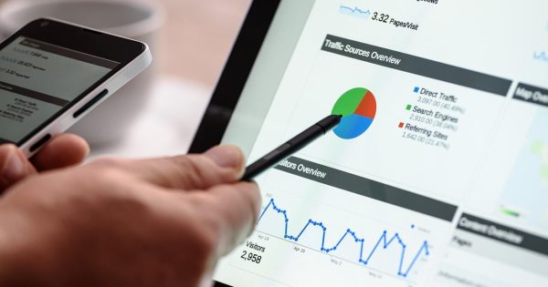 Mână care analizează grafice și date SEO pe un laptop, esențială pentru a înțelege și demonta mitul canibalizarea cuvintelor cheie și a identifica adevăratele probleme de ranking.