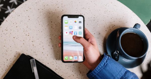 O mână care ține un telefon cu aplicațiile Instagram și Facebook pe ecran, ilustrând datele conform cărora Instagram depășește Facebook în UE.